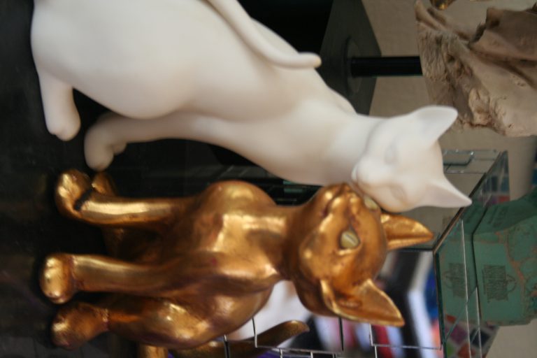 A staue of a white and a golden cat